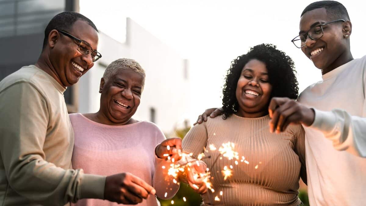 Happy African family celebrating holidays with sparklers fireworks at house party